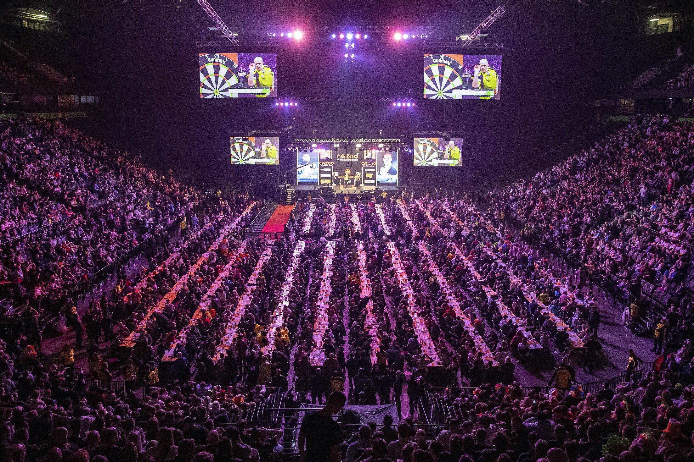 auf dem Bild ist eine Arena zu sehen, in der gerade ein Darts Turnier mit zuschauern stattfindet