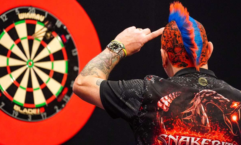 ein Mann von hinter der eine Dartsscheibe genau betrachtet